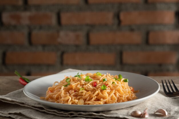 O macarrão está em um prato branco redondo, colocado sobre uma mesa de madeira. conceito de macarrão com espaço de cópia