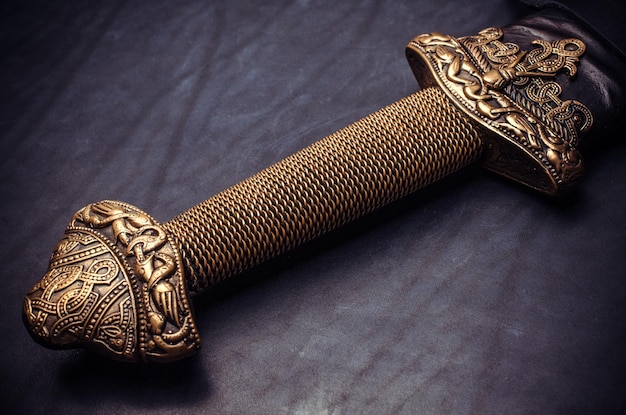 O magnífico cabo de bronze da espada em uma trança espiral em um fundo preto