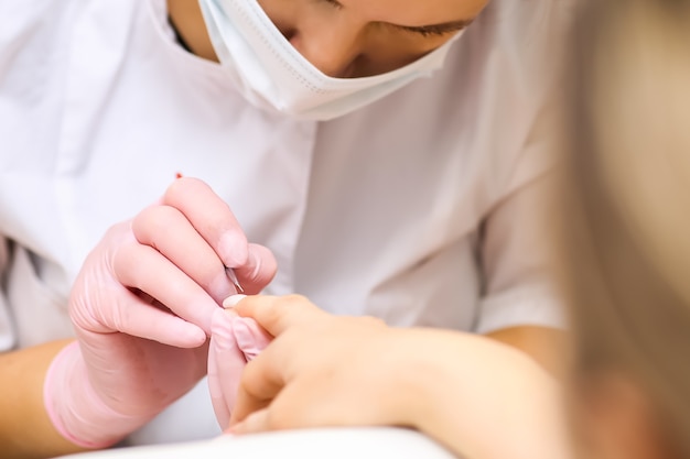 O manicure mestre desenha as unhas e mergulha no trabalho.