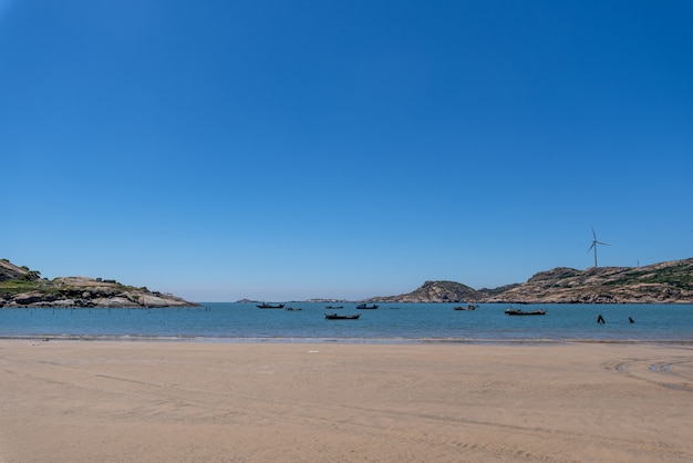 Foto o mar sob o céu azul, praias limpas e água do mar, assim como ilhas e moinhos de vento