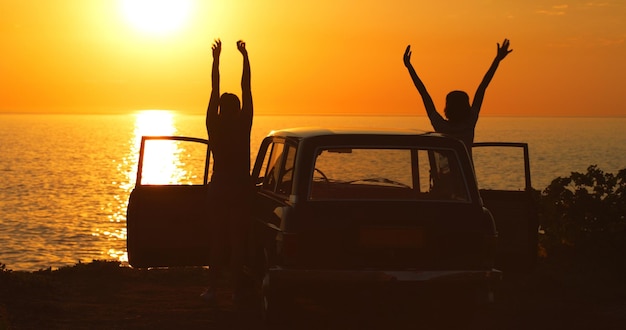 O mar traz à tona suas garotinhas interiores Foto retrospectiva de duas amigas irreconhecíveis torcendo com os braços levantados durante uma viagem na praia