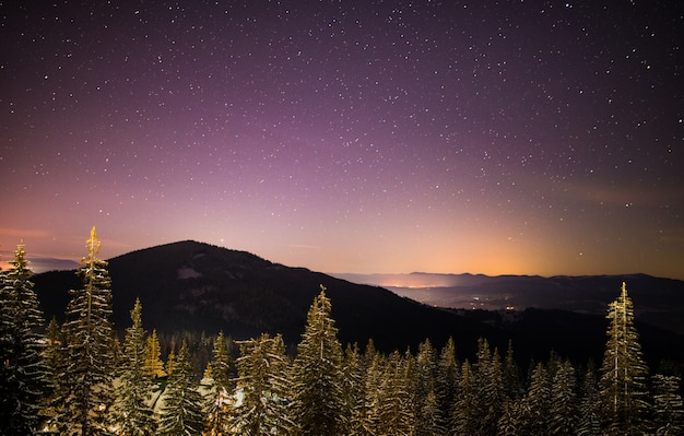O maravilhoso céu estrelado está localizado acima das vistas pitorescas da estação de esqui entre as montanhas de colinas e árvores