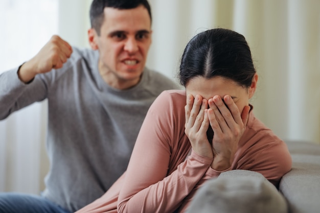 O marido alcoólatra bate na esposa com o punho. zhenzhina se cobre com as mãos. violência na família