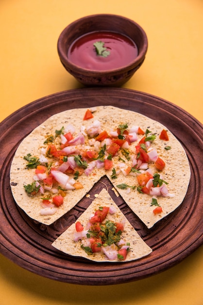 O Masala papad é uma entrada ou comida crocante vegetariana indiana que é muito fácil de preparar. Servido com ketchup de tomate sobre um fundo mal-humorado. Foco seletivo