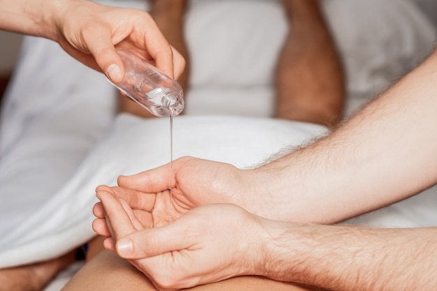 Foto o massageador derrama óleo nas palmas das mãos durante a massagem nas costas da mulher.