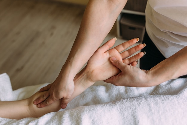 O massagista faz massagem na mão feminina no spa