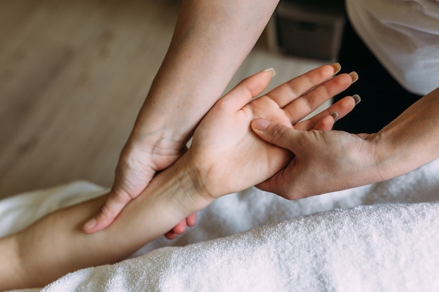 O massagista faz massagem na mão feminina no spa