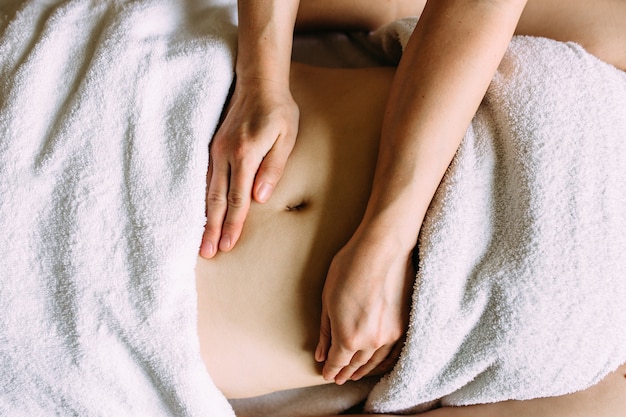 O massagista faz massagem no ventre feminino no spa