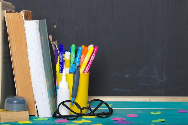 O material escolar de volta à escola está sobre a mesa. Fundo do quadro-negro