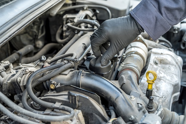 O mecânico está abrindo a tampa do óleo para troca de óleo do motor de um carro. auto-serviço