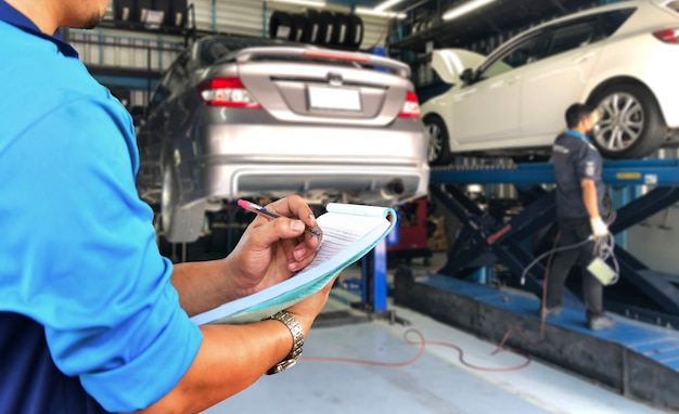 O mecânico está verificando o serviço de conserto da parte inferior do carro na garagem.