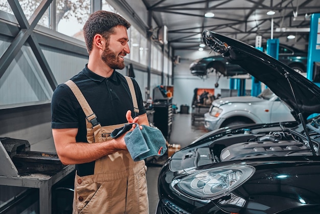 O mecânico limpa as mãos depois de reparar o carro Vista lateral