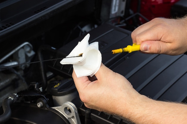 O mecânico verifica o nível de óleo no carro