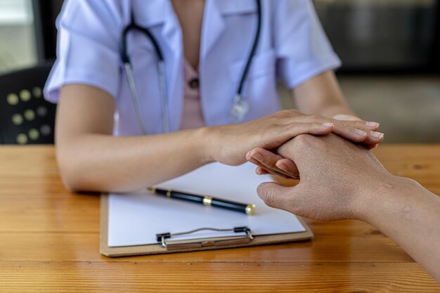 O médico aperta as mãos para encorajar o paciente depois que os resultados do diagnóstico são concluídos, o paciente detectou uma doença grave nos estágios iniciais. Conceito de diagnóstico de doenças.