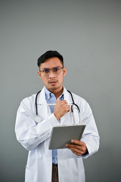 O médico asiático profissional está segurando o fundo cinza isolado do tablet