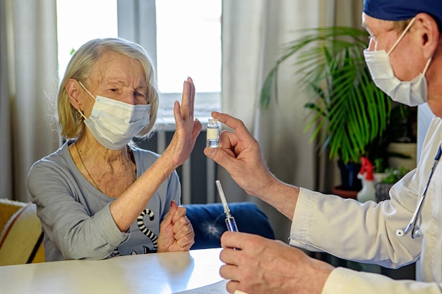 O médico atencioso ajuda uma avó idosa negativa de 85 anos - um paciente em casa ou no hospital.