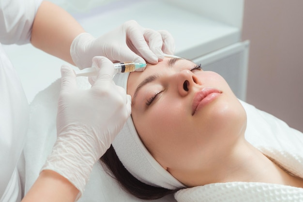 O médico cosmetologista faz o procedimento de injeções faciais rejuvenescedoras para apertar e