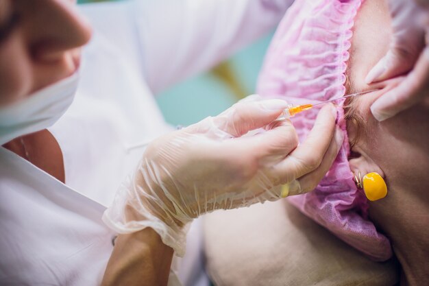 O médico cosmetologista faz o procedimento de rejuvenescimento das injeções faciais