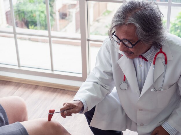 O médico está examinando o joelho do paciente