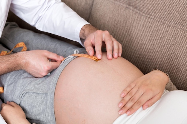 O médico está medindo a barriga crescente de sua paciente grávida em casa Conceito de gravidez Close-up