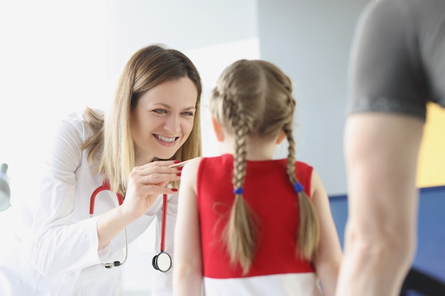 O médico examina a garganta e a boca da menina, o tratamento da amigdalite em crianças.