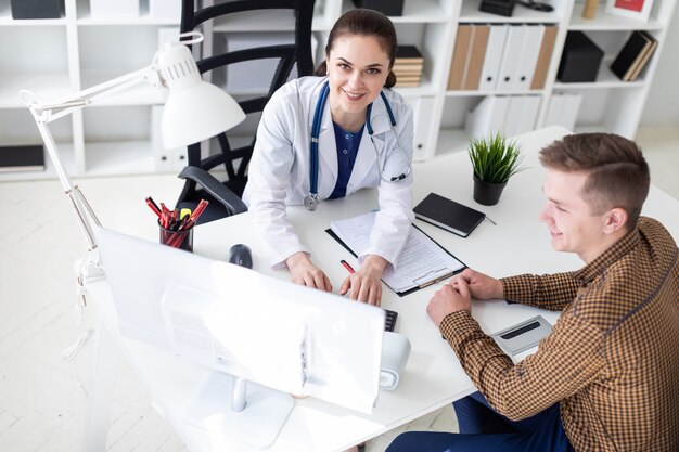 O médico explica o problema ao paciente no computador.