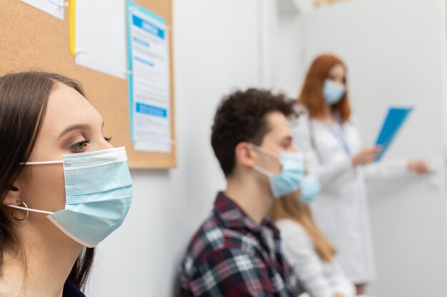 O médico lê a próxima pessoa na fila durante uma pandemia todos devem usar máscaras de proteção