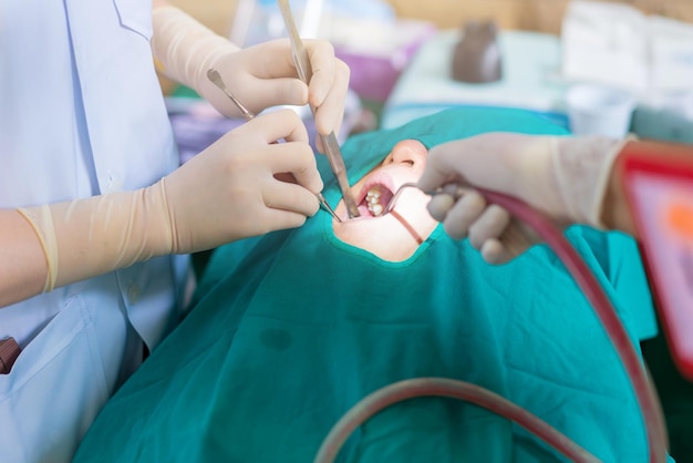 Foto o médico limpando os dentes do paciente com uma ferramenta ultrassônica