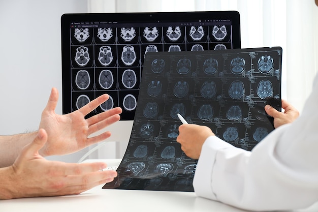O médico mostra o tumor ao paciente em imagens de ressonância magnética da cabeça