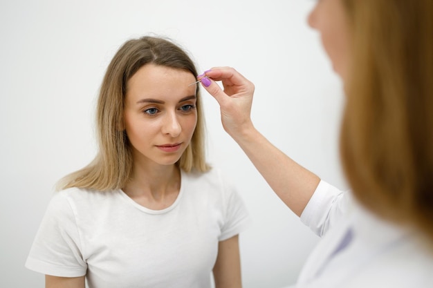 O médico neurologista está verificando a sensibilidade do paciente feminino com agulha especial