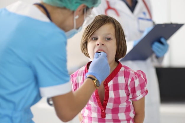 O médico olha para a garganta da menina no escritório