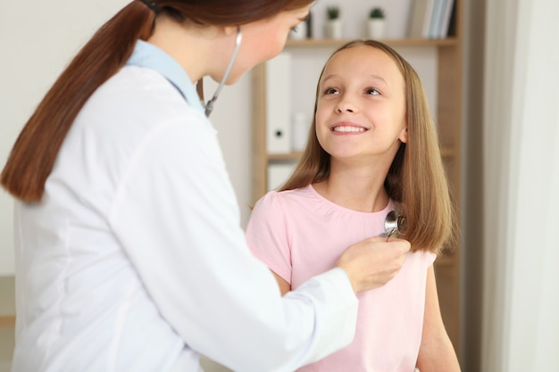 O médico pediatra jovem faz um check-up a uma menina