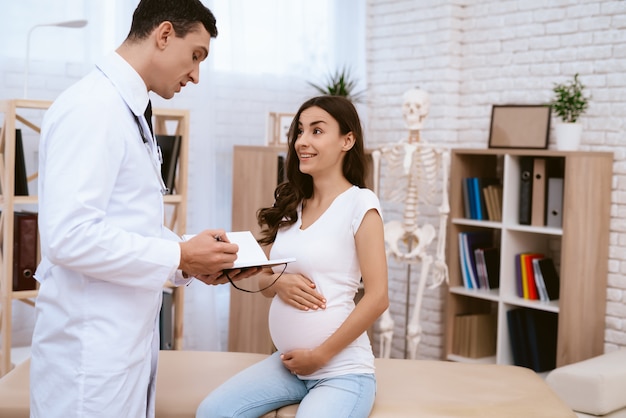 O médico registra o diagnóstico de uma menina grávida.