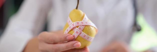 O médico sugere comer frutas e alimentos com nutricionista de vitaminas mostrando pera amarela madura com
