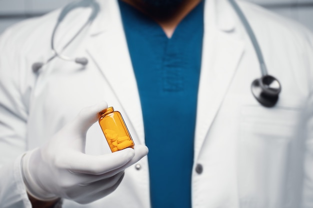 Foto o médico tem um frasco de comprimidos nas mãos