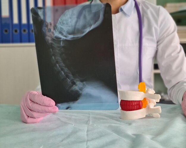 O médico traumatologista aconselha o paciente a examinar a imagem de raio-x do pescoço da coluna vertebral