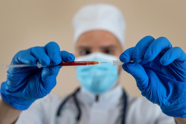 Foto o médico usa luvas brancas uniformes e máscara segurando a seringa de injecção médica isolada