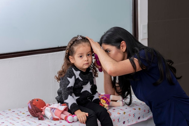 O médico verifica a orelha de uma menina com um otoscópio em sua prática médica