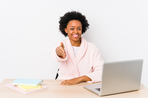 O meio envelheceu a mulher afro-americano que trabalha em casa isolada esticando a mão na câmera no gesto do cumprimento.