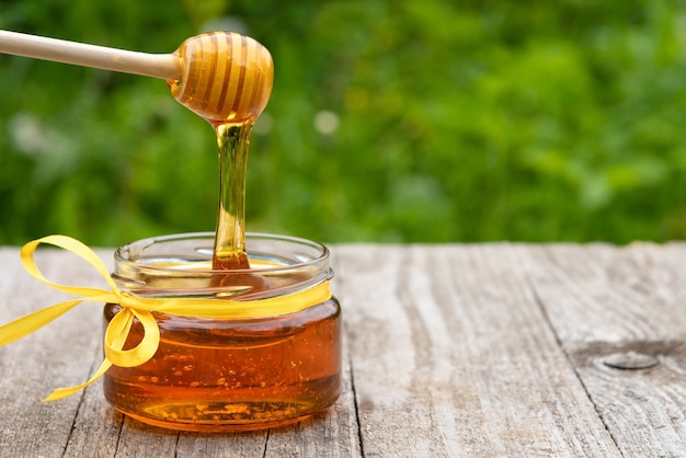O mel pinga de uma colher de pau em um pote