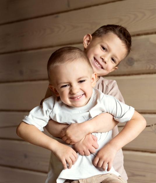 Foto o menino abraça o irmão mais novo. o irmão mais velho segura o mais novo nos braços