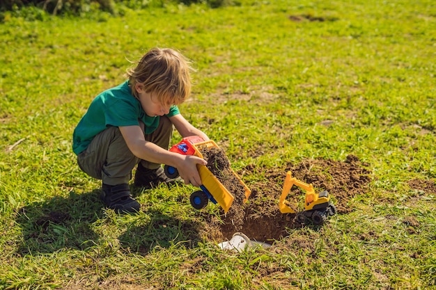 O menino brinca de reciclagem Ele enterra pratos descartáveis de plástico e pratos biodegradáveis