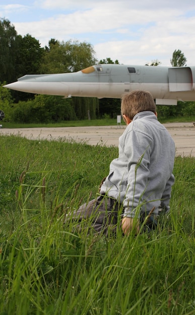 O menino brinca na grama em frente aos mísseis de cruzeiro perto dos bombardeiros estratégicos na pista