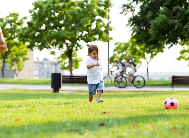 O menino brincando com bola no parque.