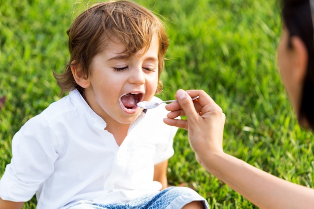 O menino comendo iogurte no parque.