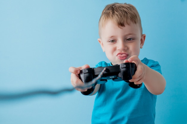 O menino da criança 2-3 anos de idade que veste a roupa azul guarda o manche disponivel para o retrato azul do estúdio das crianças do fundo do gameson. conceito de estilo de vida de infância de pessoas. zombar do espaço da cópia