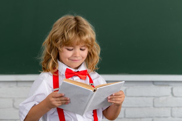 O menino da escola lê um livro na sala de aula De volta à escola primeiro dia na escola