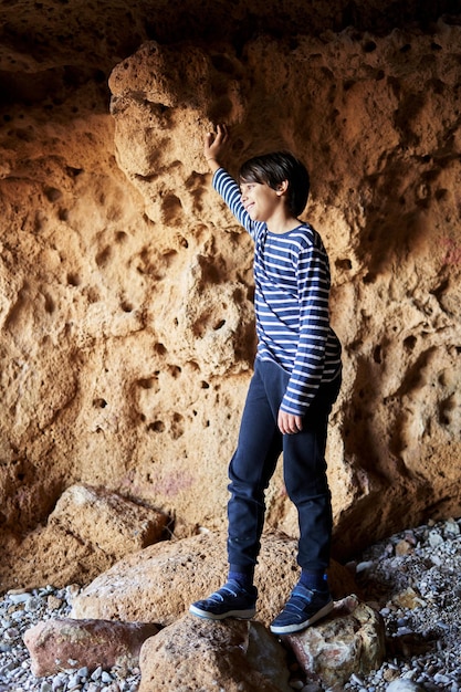 O menino de pé em uma pedra na caverna