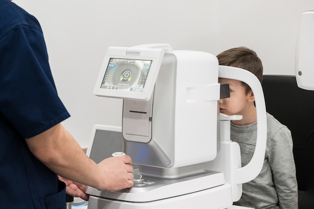 O menino é o paciente na recepção do médico oftalmologista equipamento de diagnóstico oftalmológico