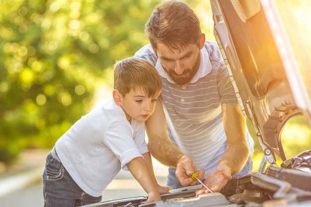 O menino e o pai verificam o nível de óleo no carro